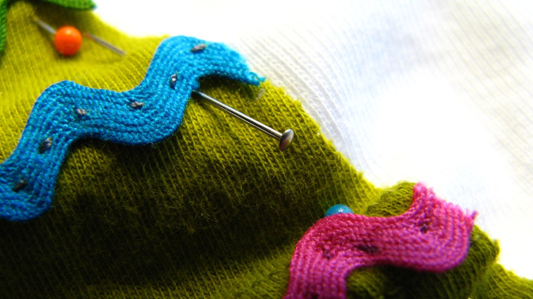 closeup macro shot of turquoise and pink vintage rickrack pinned to a green and white background