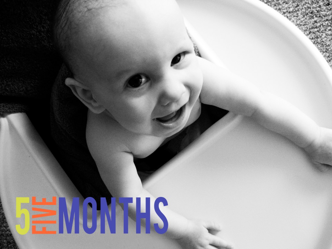 Funny black and white picture of baby Aveline in high chair making a funny face