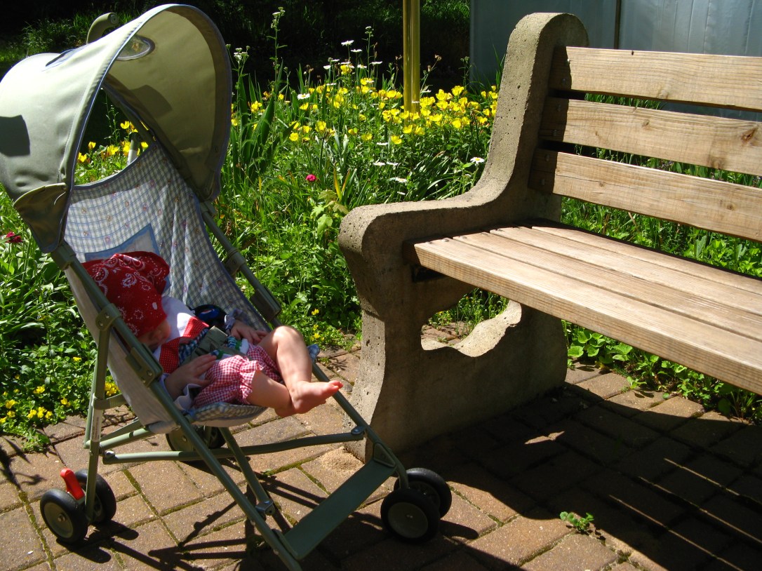 Aveline in small stroller next to garden bench