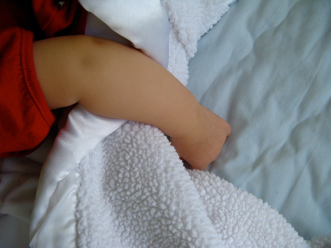 Baby's arm holding baby blanket