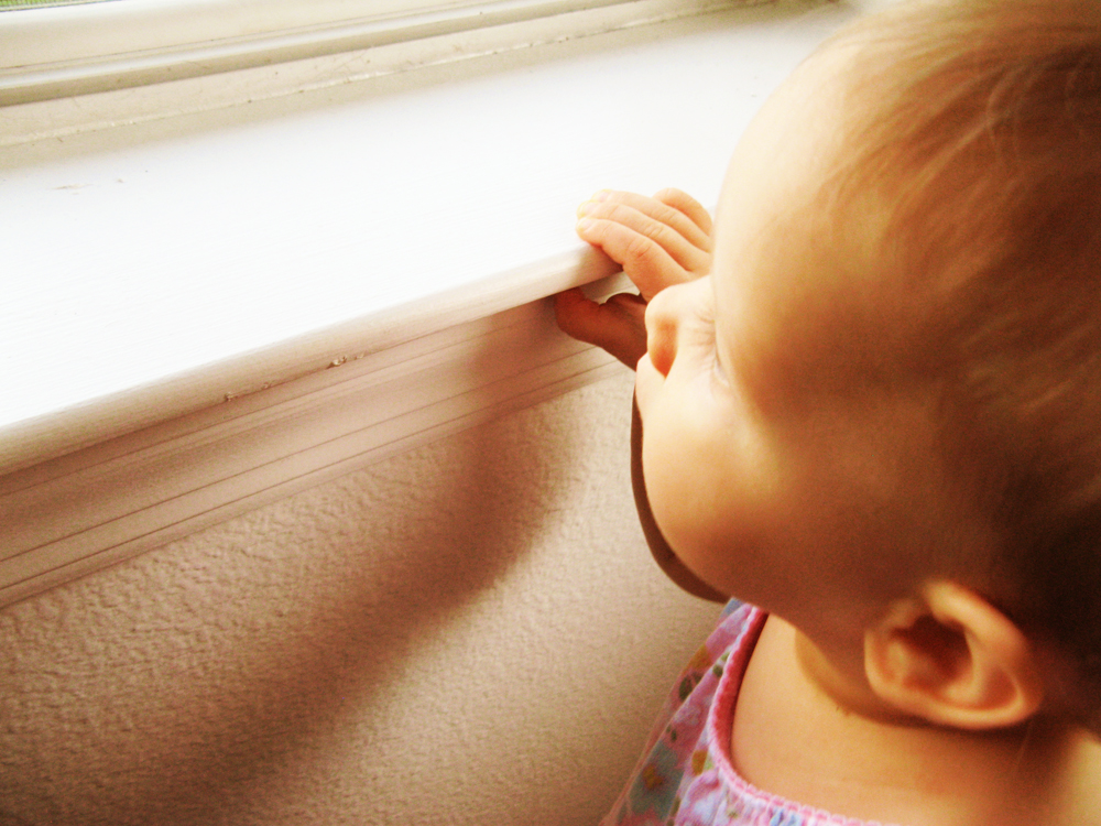 Baby peeking over top of windowsill
