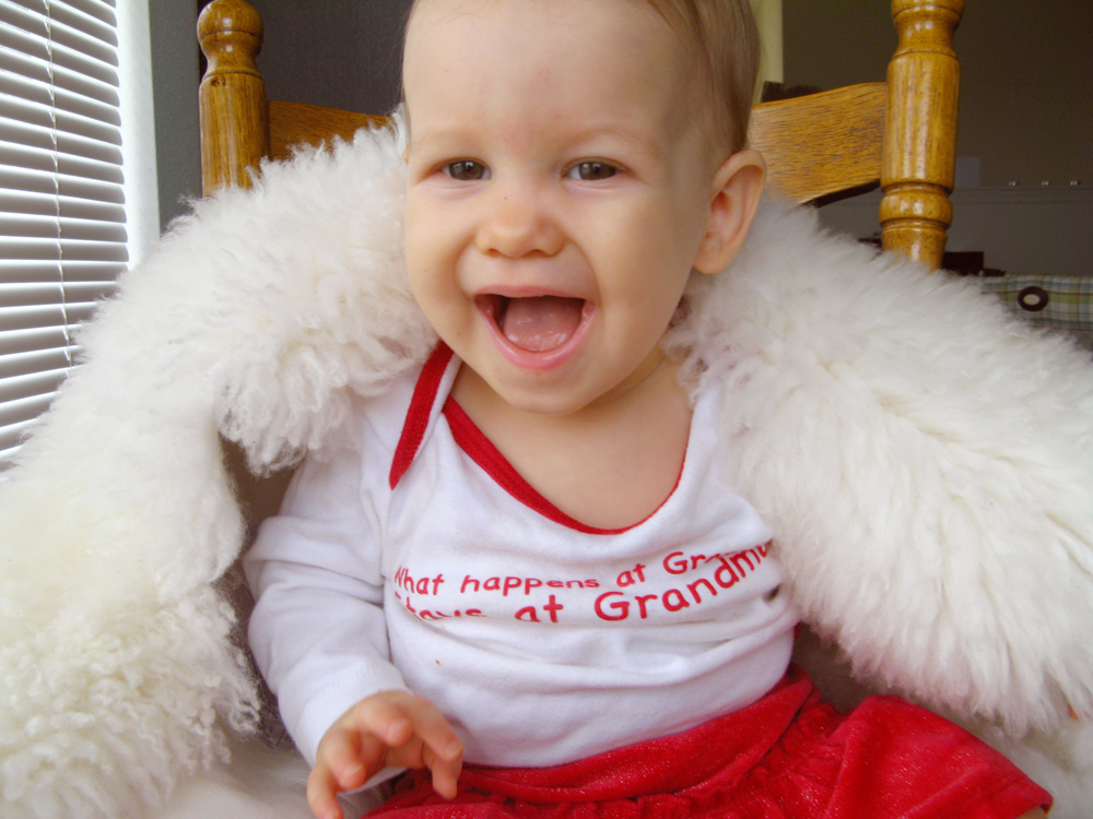 Aveline huge smile holding up sheepskin, on chair