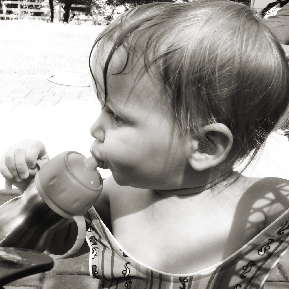 Toddler in vintage swim suit drinking from Kid Basix sippy 