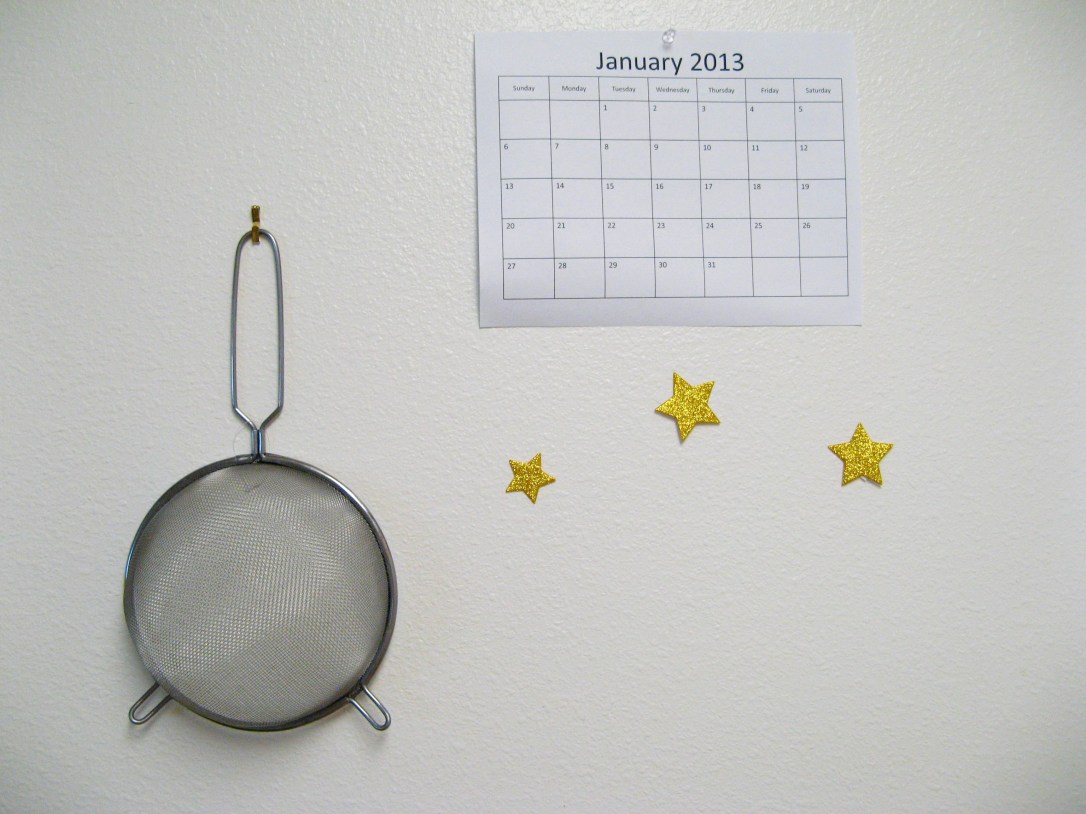 Colander, calendar, and stars on white kitchen wall - photo via Oaxaacborn dot com