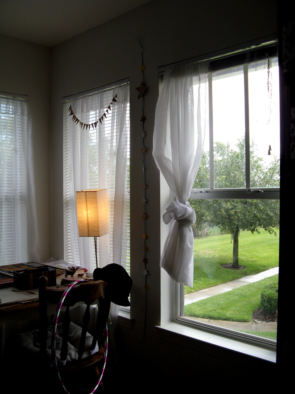 Old table in corner near window with knotted curtain