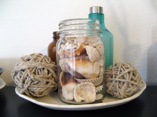 Seashells, brown and green bottles, twine, and an antique tray