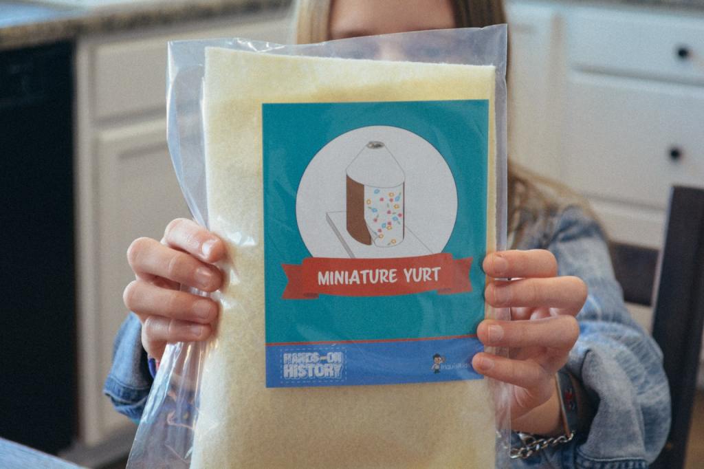 A homeschool student shows the activity kit to create a miniature yurt, from Sonlight's Hands-on History project box 