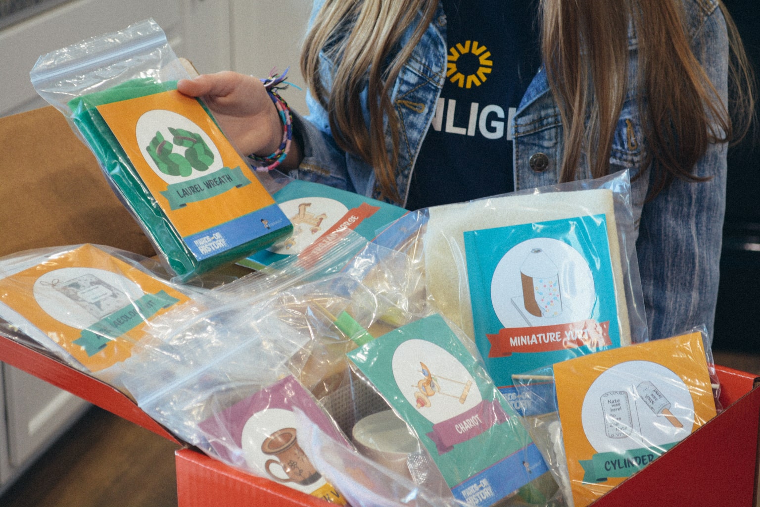 A homeschool student unboxes pre-packaged craft kits from Sonlight's Hands-on History kit 