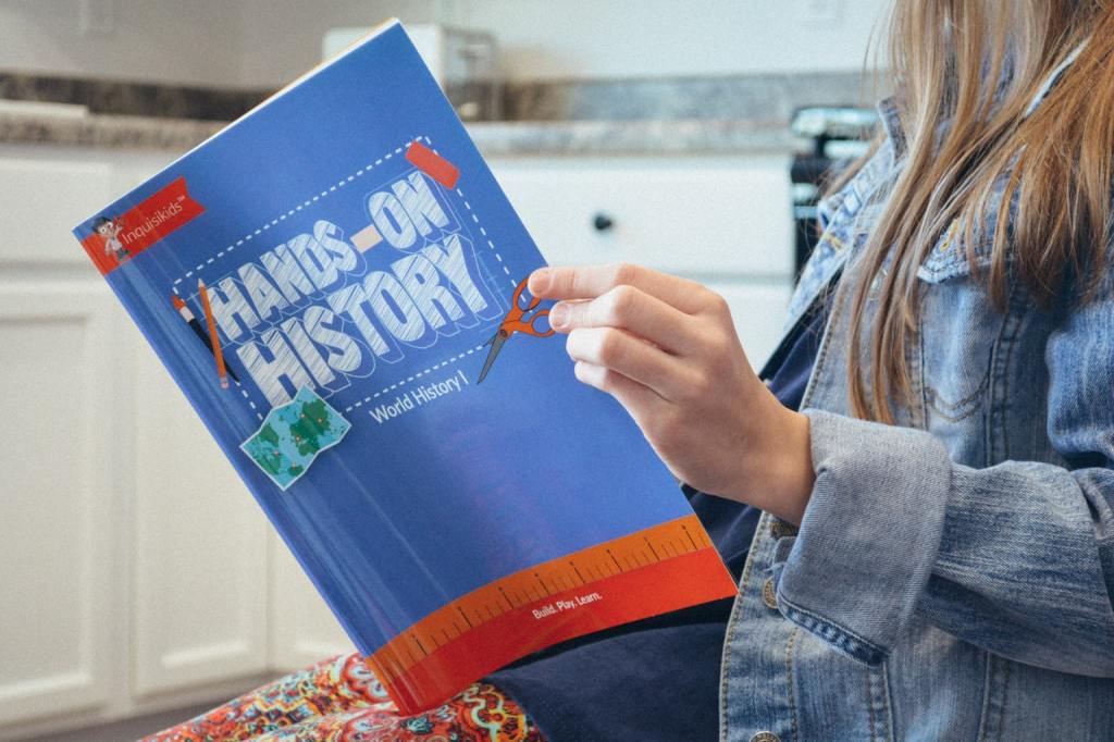 A student reads the instruction book which comes with a Hands-on History project box from Sonlight