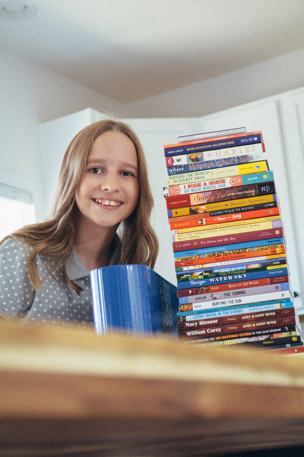 Homeschool student leans toward a tall tower of Sonlight books.
