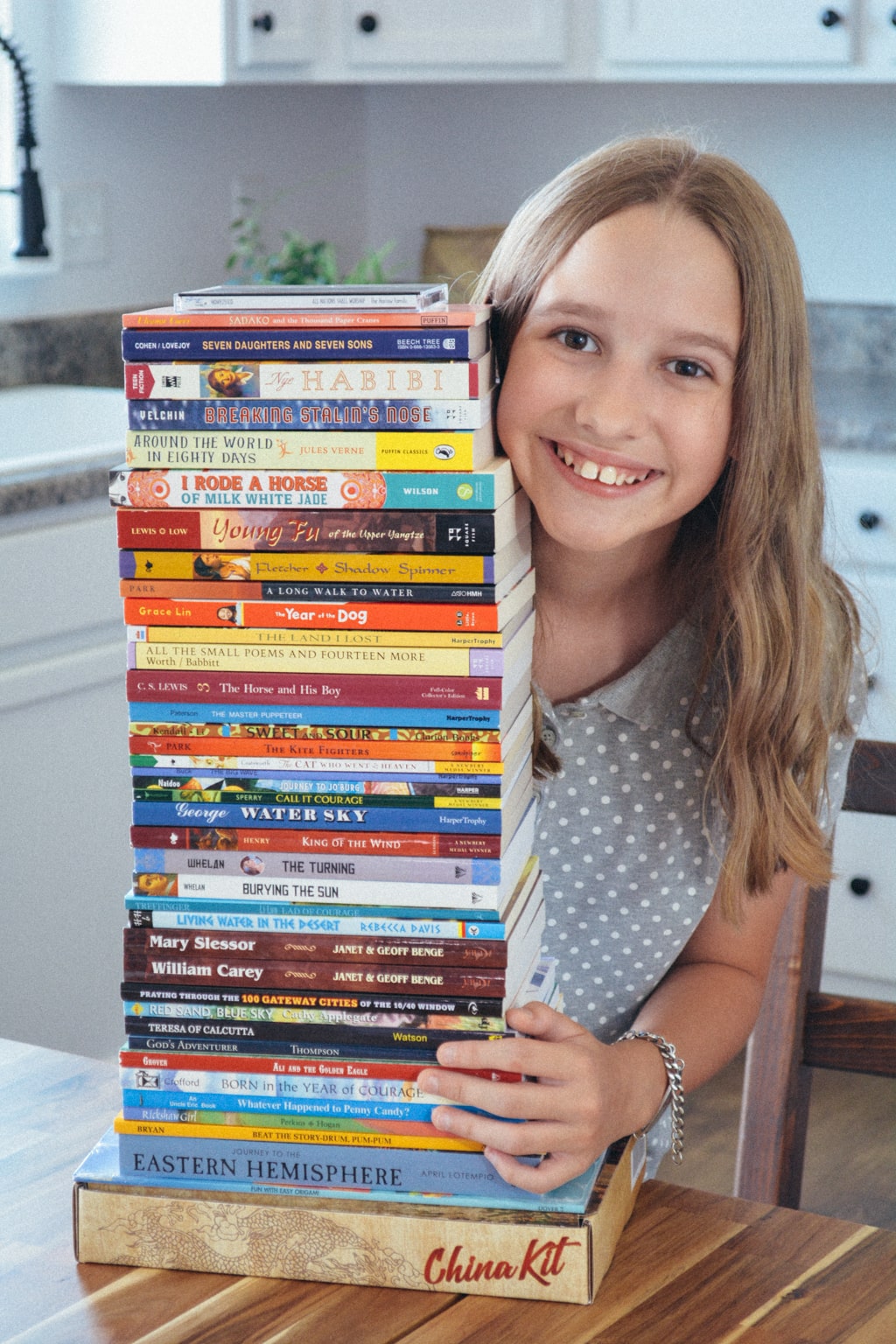 homeschool student with stack of diverse middle grade novels from Sonlight's Eastern Hemisphere curriculum