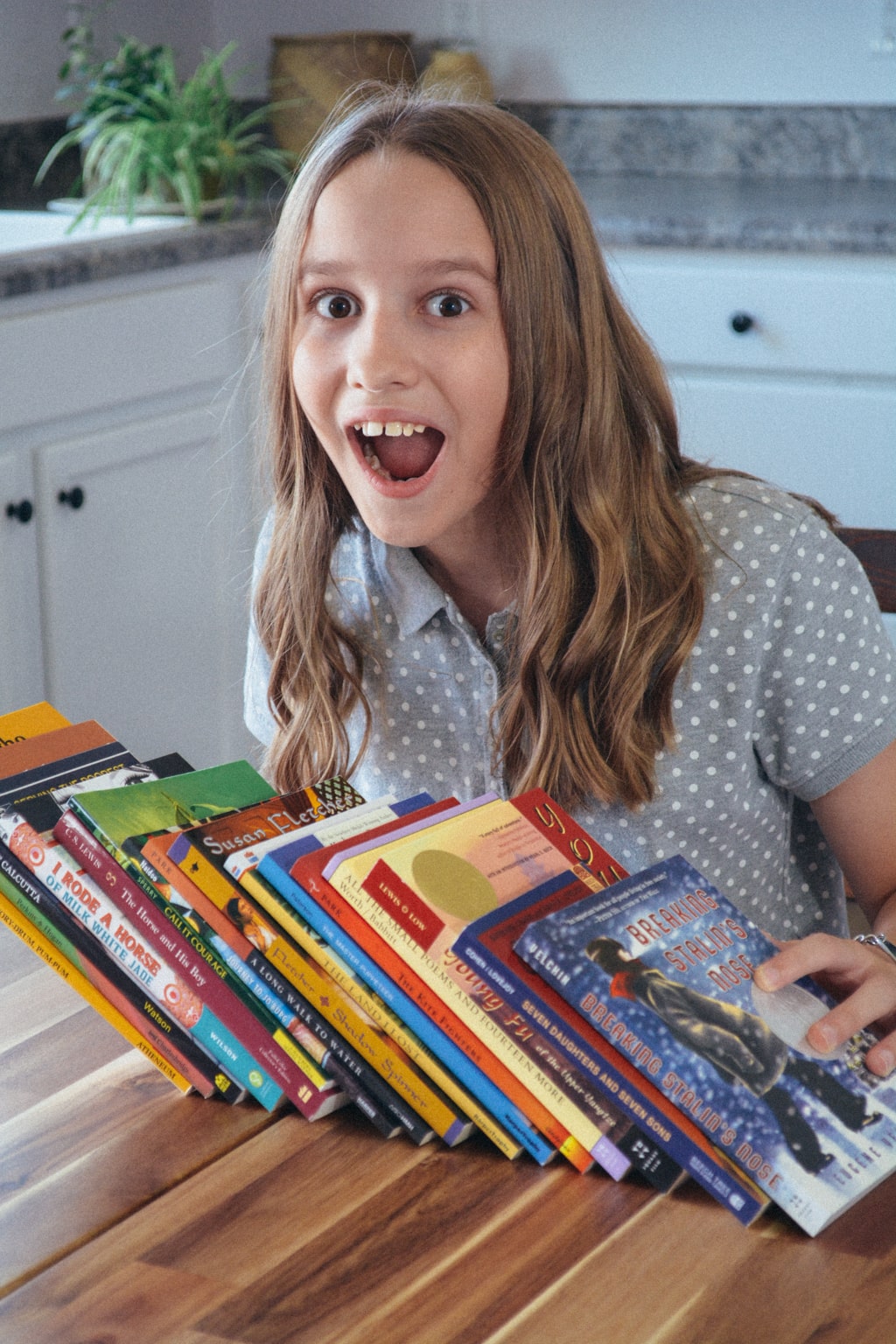 A homeschool student smiles with an array of history and literature from Sonlight Curriculum.