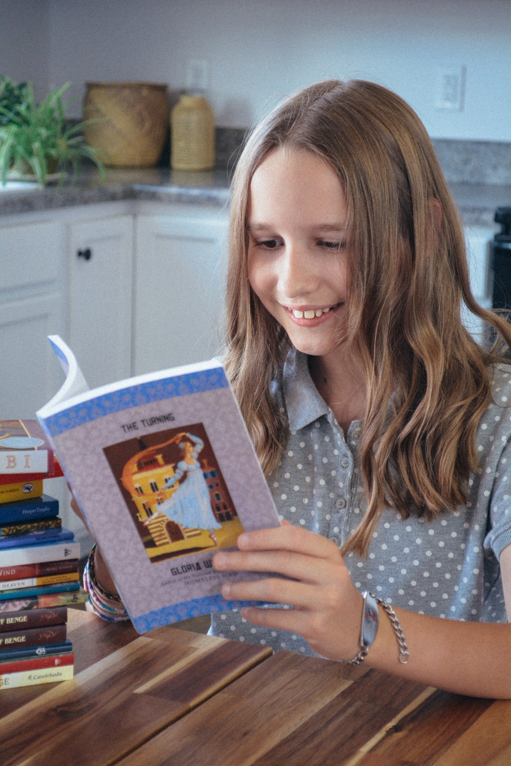 Smiling homeschool student sits at the table reading The Turning by Gloria Whelan, one of the books about the Eastern Hemisphere in Sonlight Curriculum's Level F