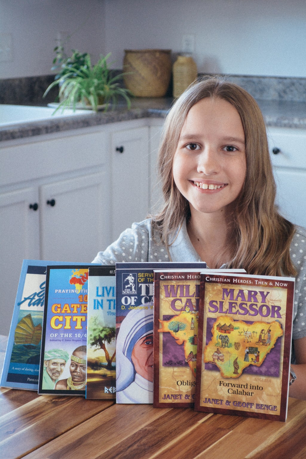 A homeschool student smiles next to an array of missionary stories.