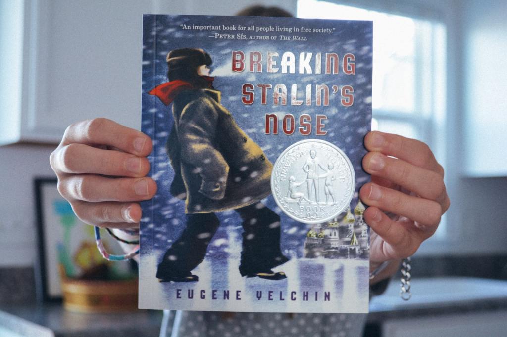 Homeschool students holds a copy of Breaking Stalin's Nose by Eugene Yelchin